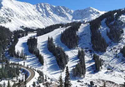 Colorado'daki Arapahoe Basin kayak merkezinde karla kaplı alt pistler, ağaçlar arasındaki parkurlar ve arkada karlı zirveler