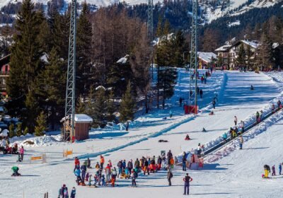 Crans-Montana'da güneşli bir kış gününde başlangıç pisti, yürüyen bant ve kızak kayan çocuklar