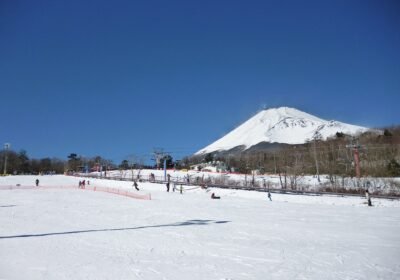 Fuji Dağı eteklerindeki Snow Park Yeti kayak merkezinde karla kaplı pist, telesiyejler ve arkada karlı Fuji zirvesi
